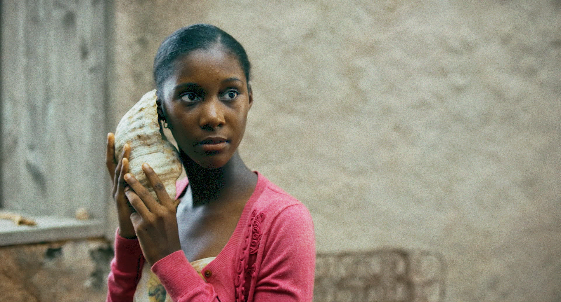 Bild på en kvinna som håller en snäcka mot sitt öra