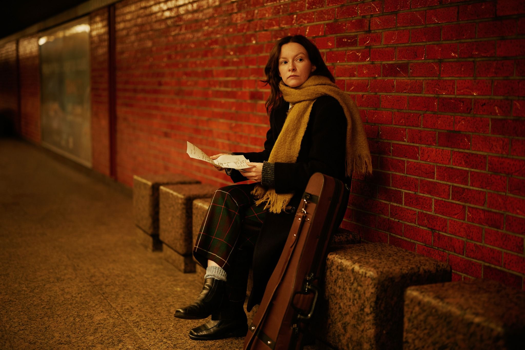 kvinna som sitter på en bänk och har ytterkläder på sig. 