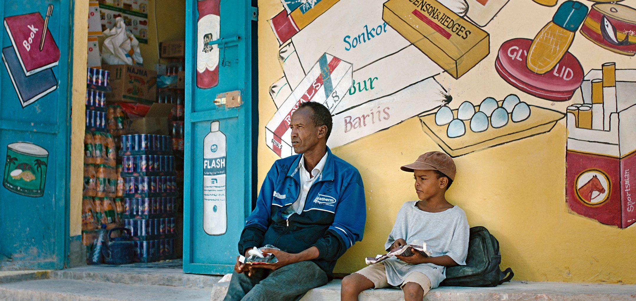 en man och ett barn som sitter utanför en affär